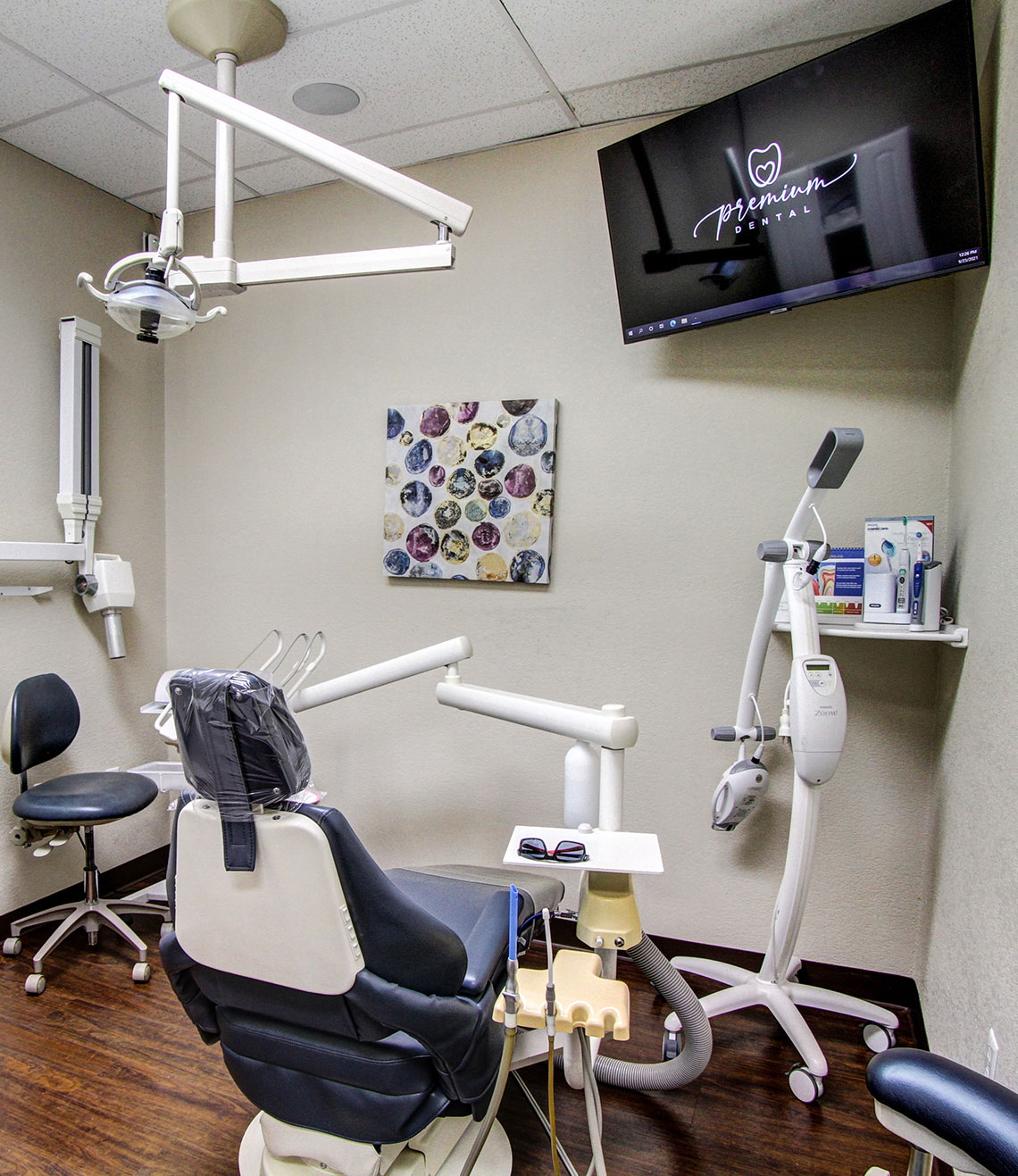 The image depicts a dental office interior with various pieces of equipment, including a dental chair, examination table, and dental tools.